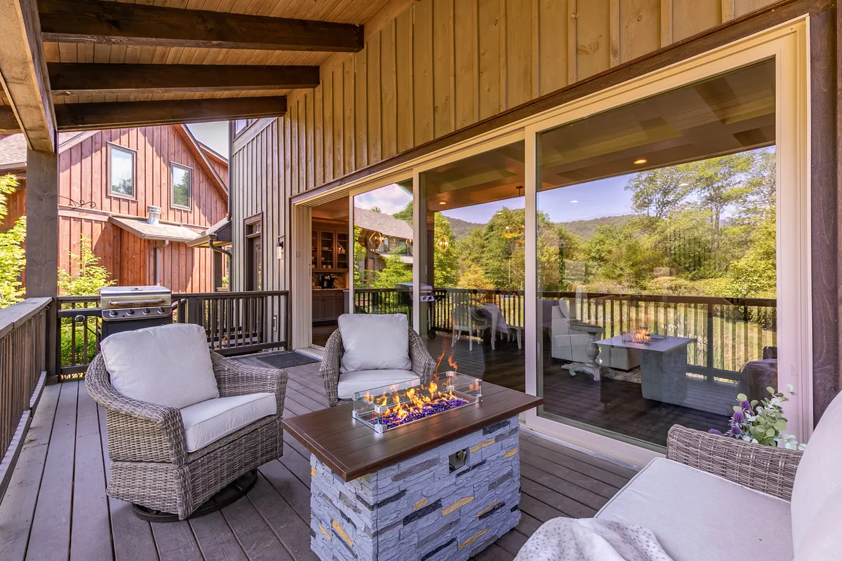 A cozy deck with a fire table and comfortable seating, all facing a beautiful view of the mountains. The scene is perfect for outdoor dining or socializing, with the warmth of the fire and fresh mountain air.