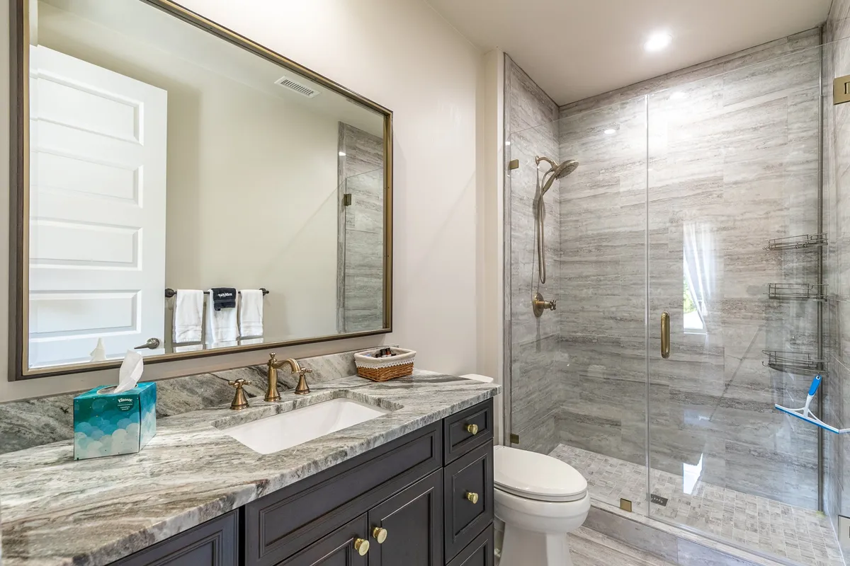A luxurious bathroom with a vanity and sink, large mirror, and a spacious shower area. The setting is serene and inviting, suggesting a space for refreshing baths or self-care routines after a day outdoors.