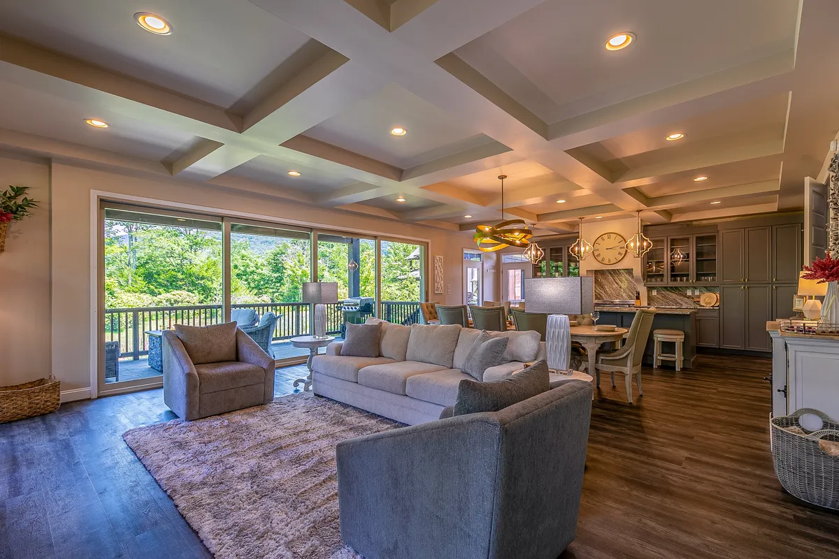 The image captures a bright, inviting living and dining space with a comfortable sofa, a spacious dining table perfect for gatherings, and large windows that flood the room with natural light. A stylish light fixture hangs above, setting a warm, welcoming tone for the space.